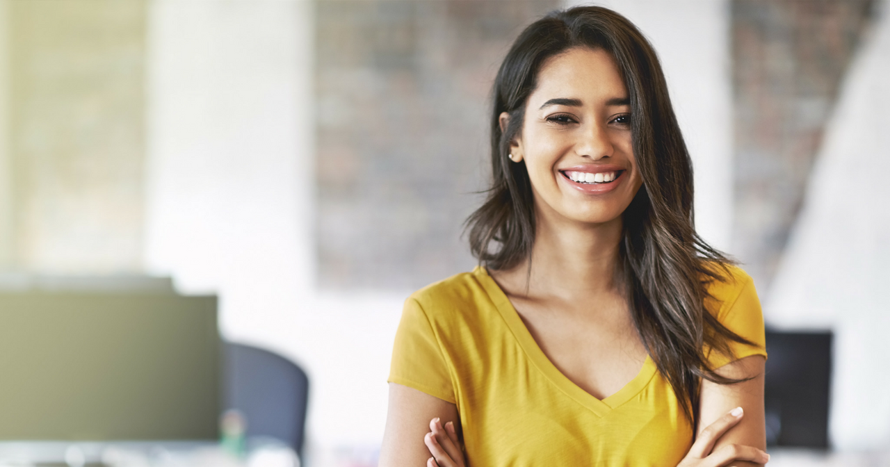 A woman with her arms crossed smiles