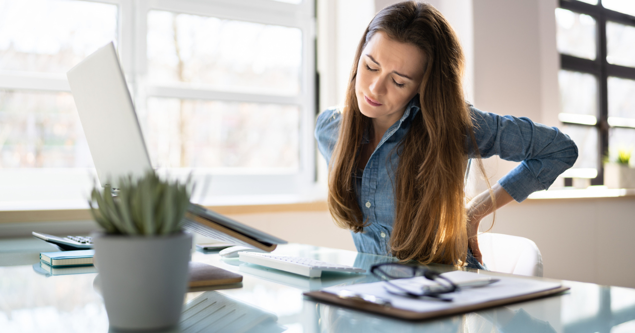 A woman sits at a desk and considers her screen while looking concerned. 