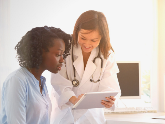 A provider looks down at a tablet and explains something to a patient. 