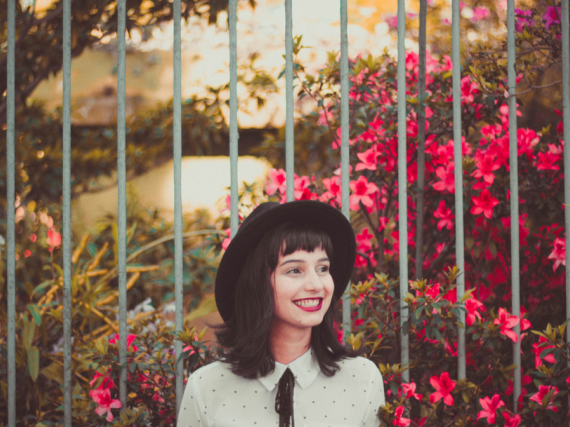 A smiling woman stands in front of flowers
