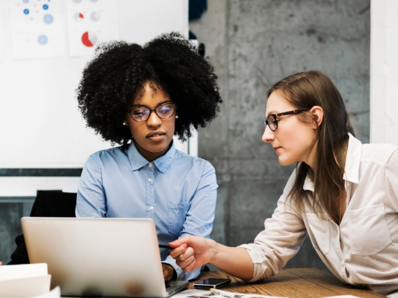Two women work at a computer together