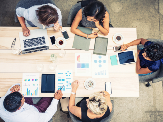 A group of five people works together at a table. 