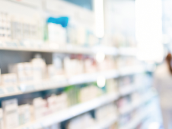 A blurry photo of a bright pharmacy shelf with lots of boxes lined up for sale.