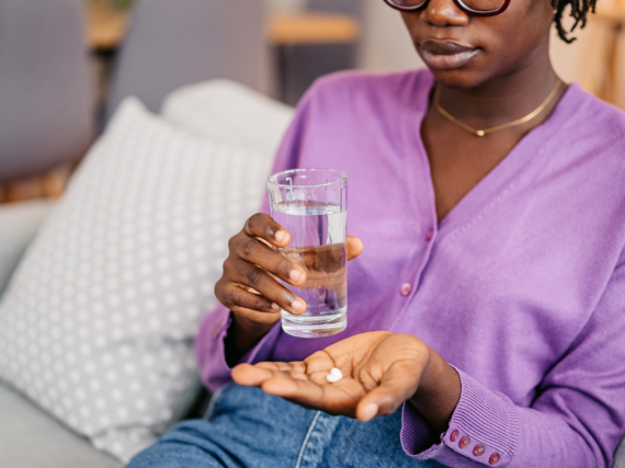Woman taking a pill with water.